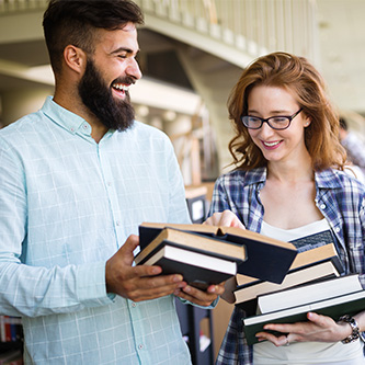 Deux adultes souriants et tenant des piles de livres